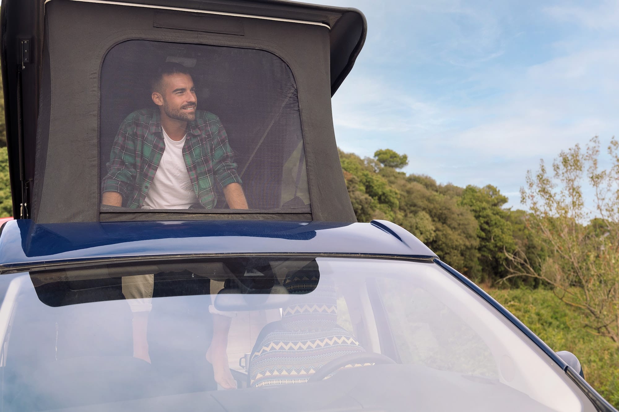 man looking the scenery from the roof of his van